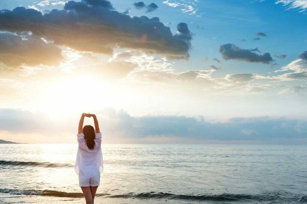 Personne face à la mer se tenant le bas du dos au début des vacances.