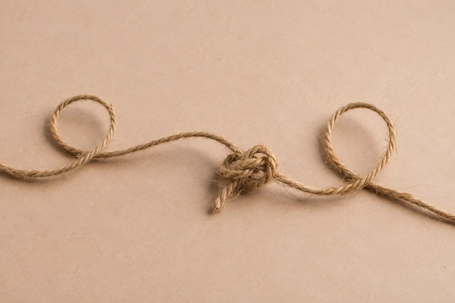 Ficelle formant deux boucles autour d’un nœud sur fond beige